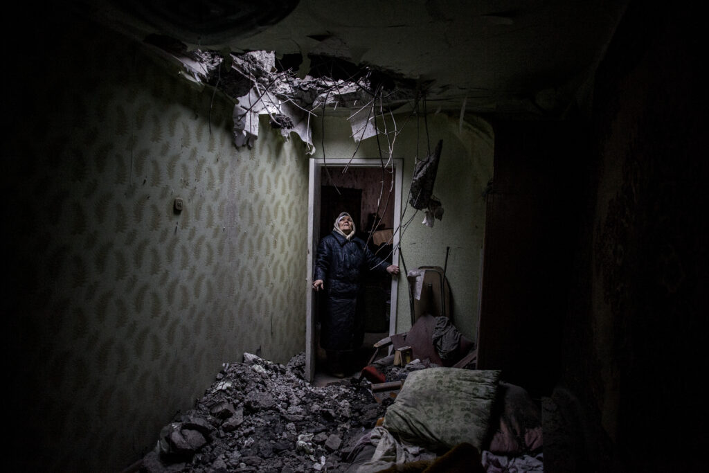 Galina, 83, looks at the hole made by a Ukrainian rocket at the roof of her flat in downtown Donetsk, Ukraine, January 2015.